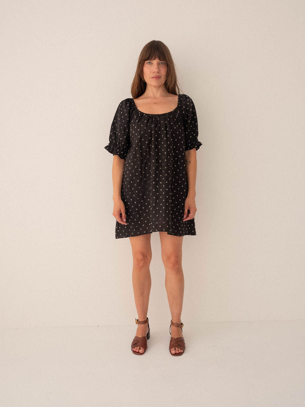 Woman wearing a black polka dot dress against a white background